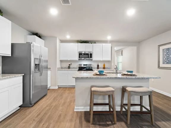 A kitchen with white cabinets and a marble countertop.