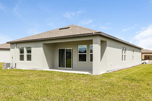 A house with a grey roof and white walls with a green lawn in front.