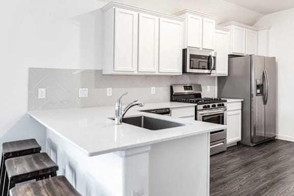 A kitchen with white cabinets and a stainless steel refrigerator.