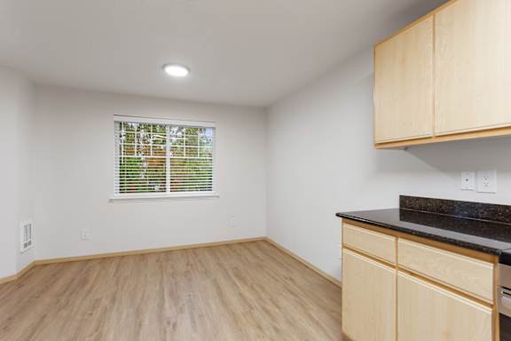 A kitchen with wooden cabinets and a window with blinds.
