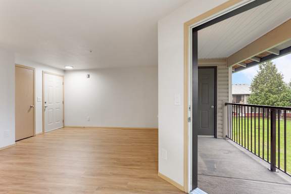 A room with wooden floors and white walls, with a black railing on the balcony.