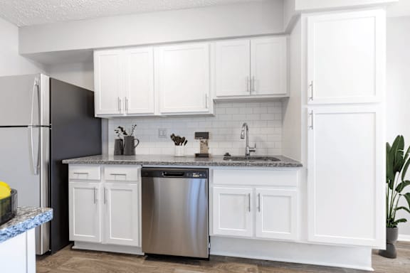 A kitchen with white cabinets and a granite countertop.