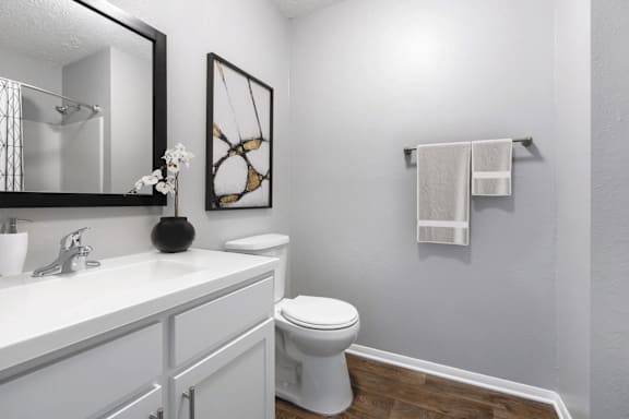 A white toilet sits in a bathroom next to a white sink.