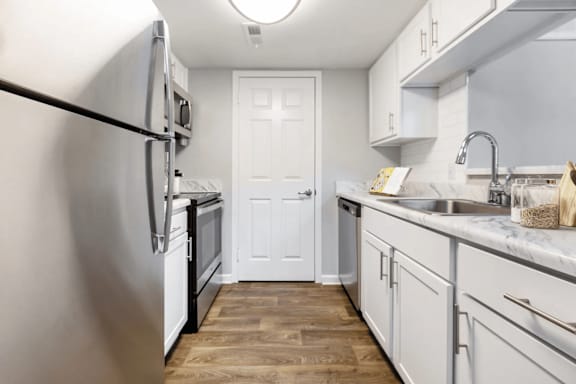 A kitchen with a white door in the middle.