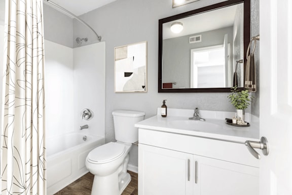 A white bathroom with a toilet, sink, and mirror.