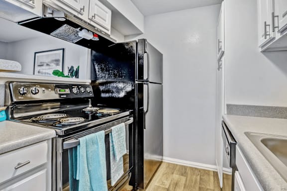 A kitchen with a black refrigerator and a stove top oven.