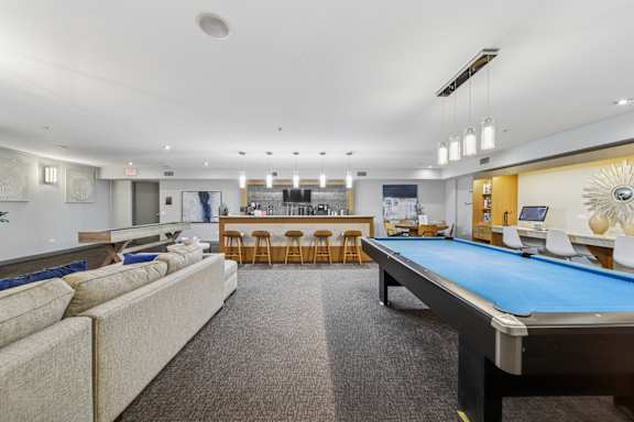 A room with a pool table and a bar area.