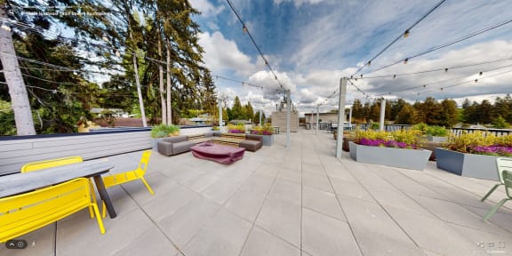 a rooftop patio with tables and chairs and plants
