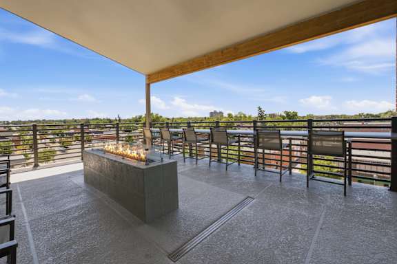 A patio with a fire pit and chairs overlooking a body of water.