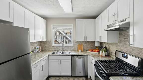 A kitchen with white cabinets and a stainless steel refrigerator.