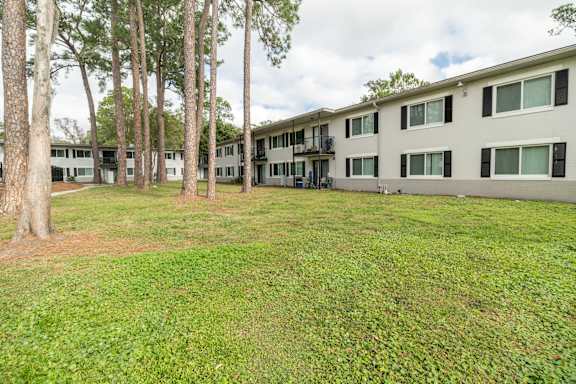A grassy area in front of a building with trees.