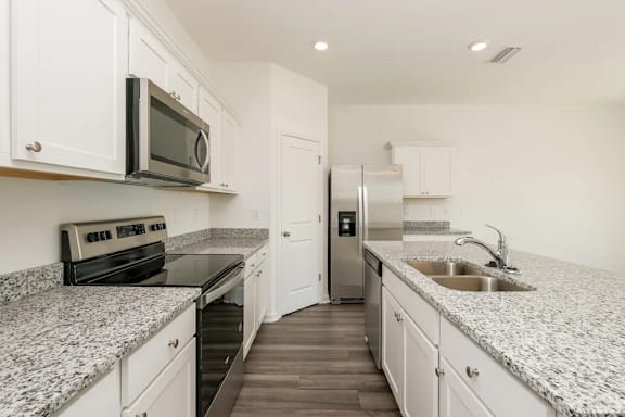 A kitchen with granite countertops and white cabinets.