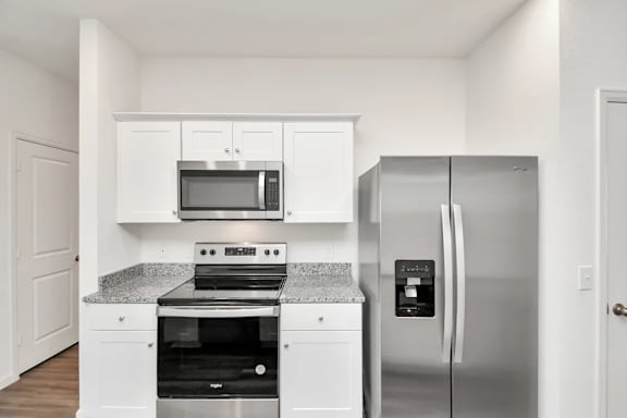 A kitchen with a stove, oven, microwave, and refrigerator.