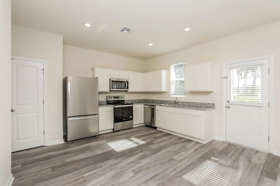 A kitchen with a refrigerator, microwave, oven, and dishwasher.