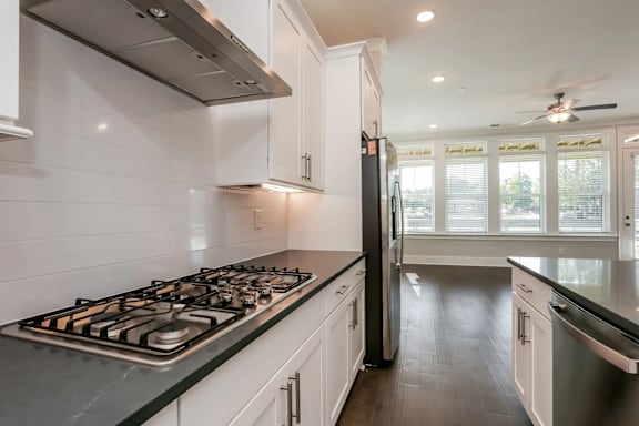 A modern kitchen with a stove top and a refrigerator.