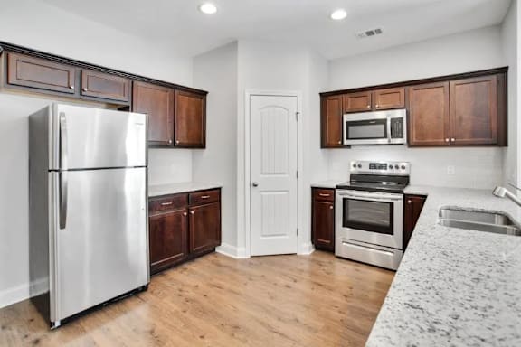 A kitchen with a refrigerator, oven, and microwave.