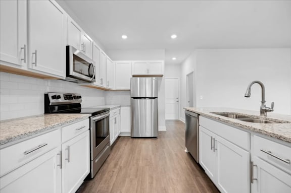 A modern kitchen with white cabinets and stainless steel appliances.