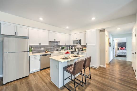 A kitchen with white cabinets and a white refrigerator.