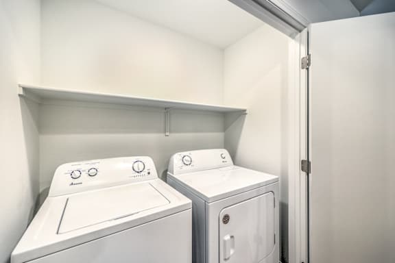 Two white front loading washing machines in a small laundry room.