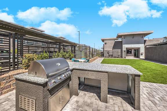A modern outdoor kitchen with a grill and seating area.