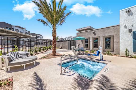 A pool surrounded by a patio with a palm tree and a building with the number 10 on it.