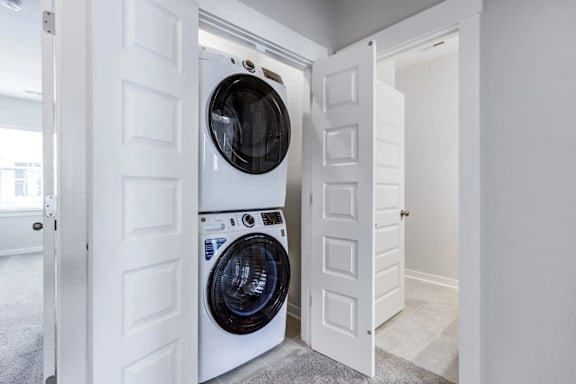 A white door is open to reveal a laundry room with a washer and dryer.