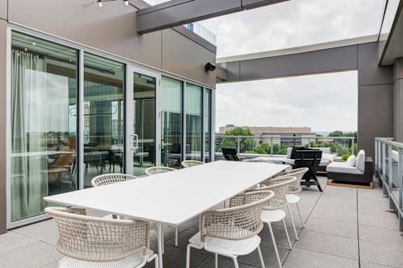 A white table surrounded by white chairs on a patio.