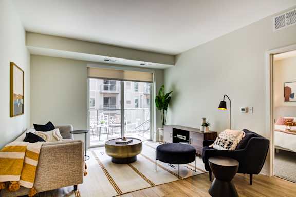 A living room with a grey couch, a black chair, and a yellow throw blanket.
