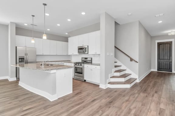 A modern kitchen with a wooden floor and white cabinets.