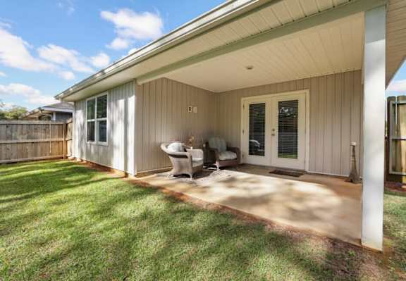 A sunny day at a house with a covered patio.