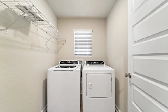 Two white front load washing machines in a laundry room.