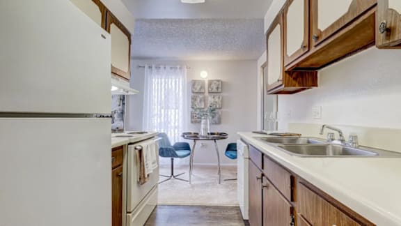 A kitchen with white appliances and wooden cabinets.