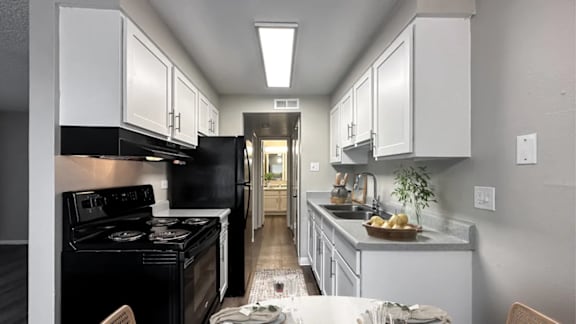 A kitchen with black appliances and white cabinets.