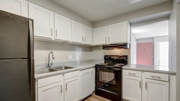 A kitchen with white cabinets and a black refrigerator.