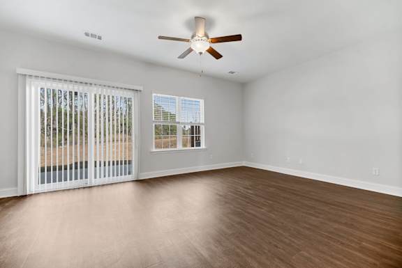 A room with a ceiling fan and sliding glass doors.