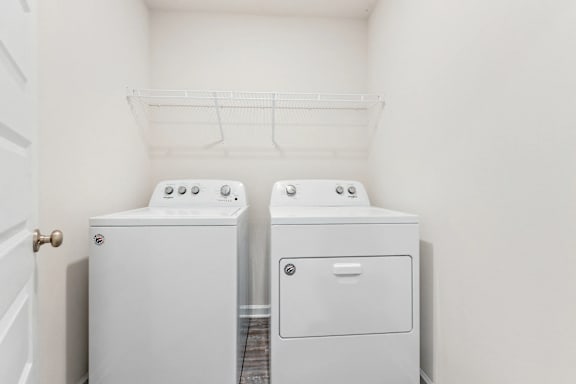 Two white washing machines in a small laundry room.