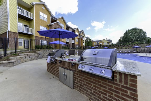 an outdoor bbq with umbrellas and apartment buildings in the background