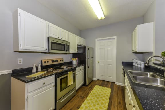 a kitchen with white cabinets and a yellow rug