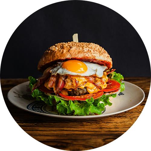 A sandwich with bacon, egg, and tomato on a plate.