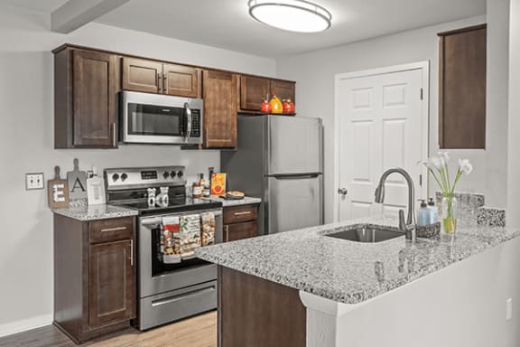 Updated Apartment kitchen in Holly, Michigan with oven, microwave, refrigerator, and granite counter tops.