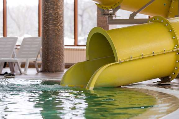 A yellow water slide in a pool.