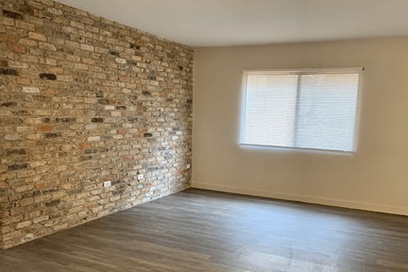 A room with beautiful exposed brick and a window with blinds.