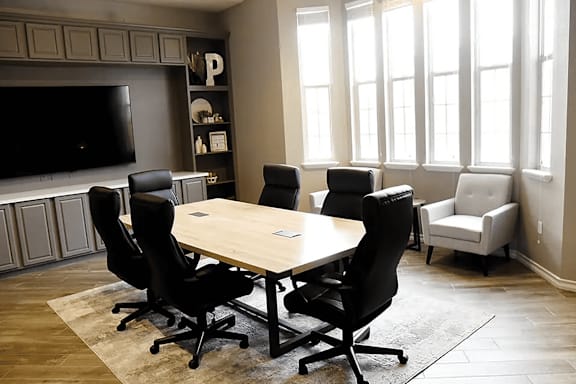 A conference room with a large table surrounded by chairs.
