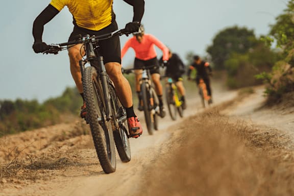 A group of people riding bikes on a dirt road.