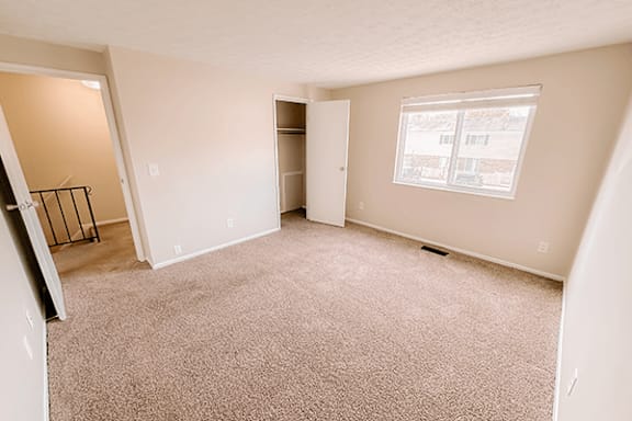 A room with a carpeted floor and a window.