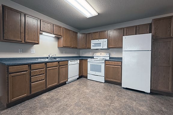 A kitchen with brown cabinets and white appliances.