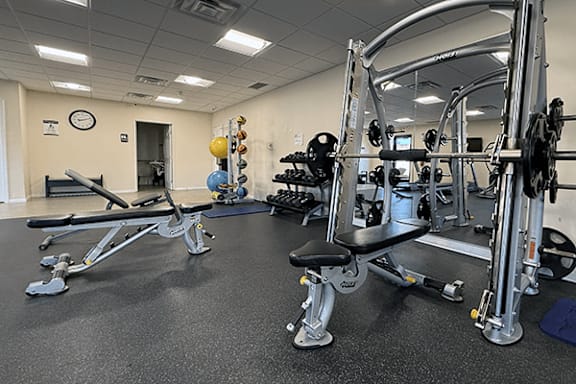 A gym with a variety of equipment including a leg press machine and a squat rack.