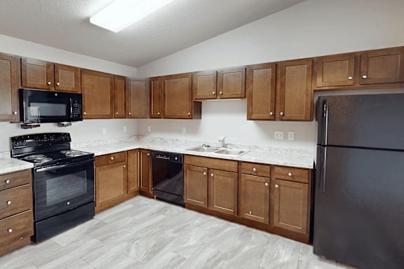 A kitchen with black appliances and wooden cabinets.