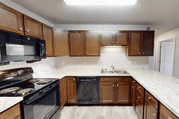 A kitchen with black appliances and wooden cabinets.