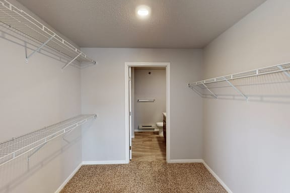A white room with a carpeted floor and a doorway leading to a bathroom.